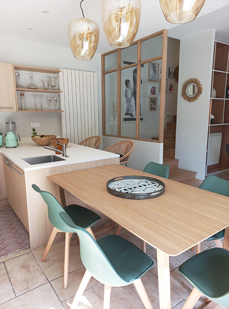 Table à manger en bois et chaises vertes acolées à l'îlot