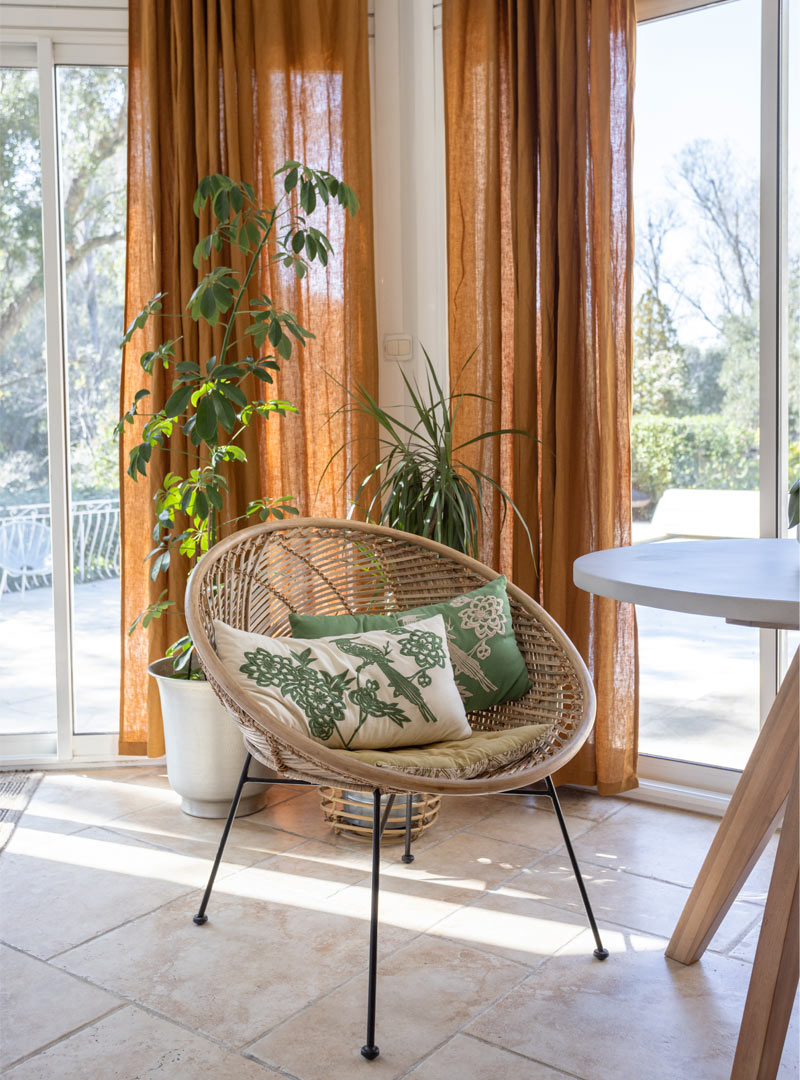 Coin salon avec fauteuil en rotin et rideaux oranges