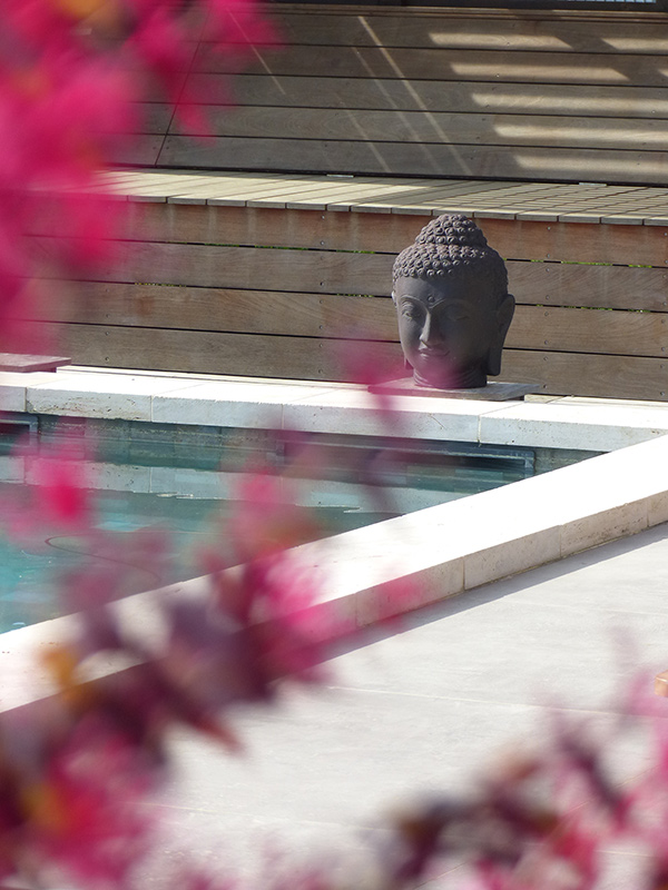 Détail zen près de la piscine – Caroline Rey, architecte d’extérieur à La Crau (Var) Tête de Bouddha décorative au bord d’une piscine bois