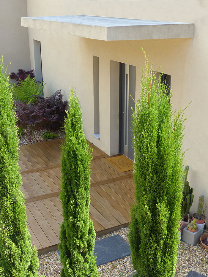 Aménagement d’entrée contemporaine – Caroline Rey, architecte d’extérieur à La Crau (Var) Vue sur entrée de maison et terrasse bois entourée de cyprès