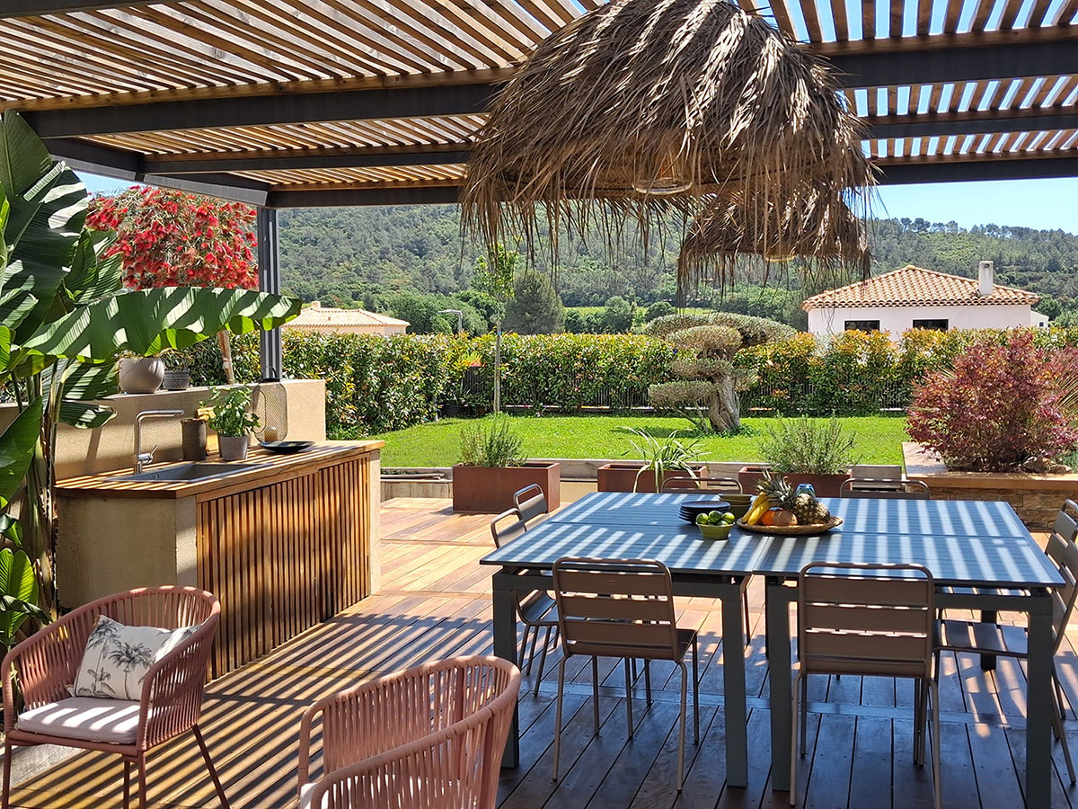 Grande terrasse avec pergola et cuisine d'été dans un style balinais Terrasse d'été sous une pergola bois et acier avec suspension fibres naturelles
