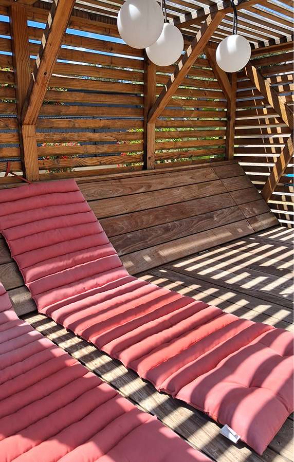 Espace lounge en bois avec transats – Caroline Rey, architecte d’extérieur à La Crau (Var) Structure bois avec bains de soleil et suspensions rondes